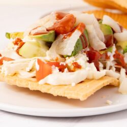 Fresh taco with avocado, tomato, shredded cheese, sour cream, and salsa on a crispy tortilla.