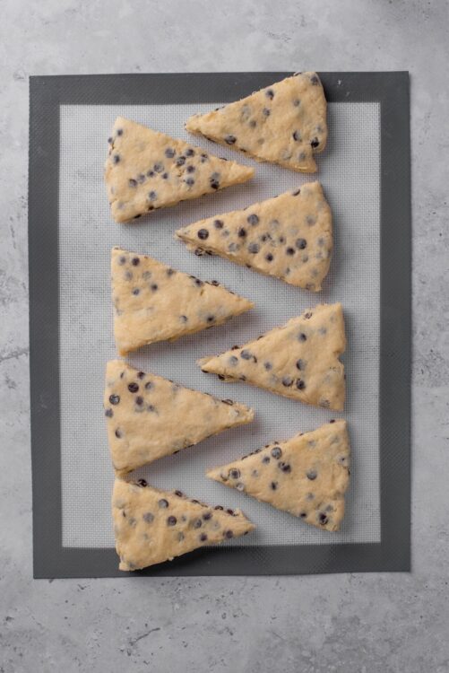 Freshly baked chocolate chip scones on a baking mat.