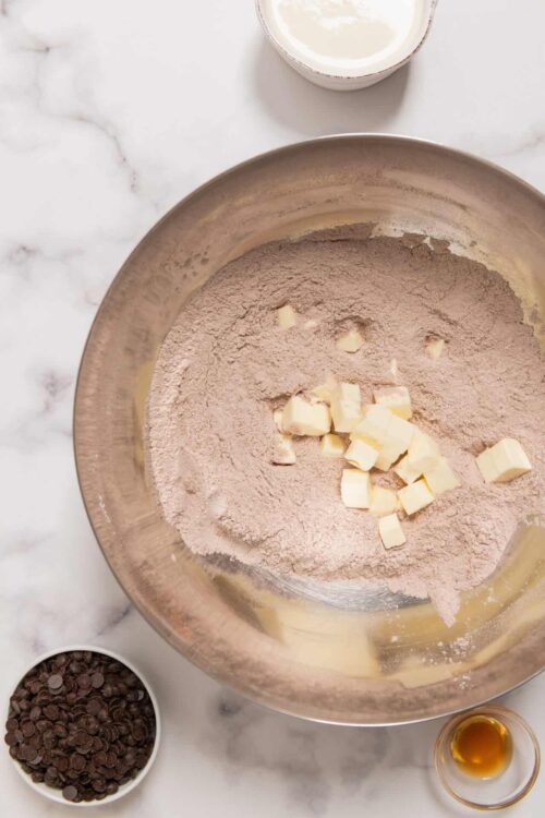 Finely ground cocoa powder and white chocolate chunks in mixing bowl for baking recipe.