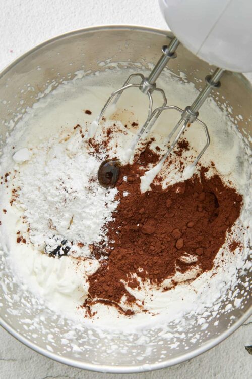 Rich chocolate cake batter with cocoa powder, flour, and cream in a mixing bowl.