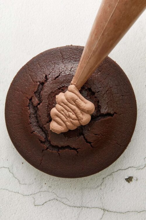 Rich chocolate bundt cake with smooth frosting and cracked surface, ready for slicing.