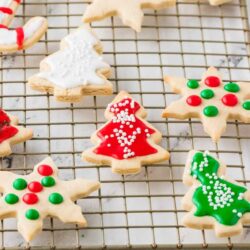 Christmas sugar cookies decorated with festive icing and sprinkles on a cooling rack.