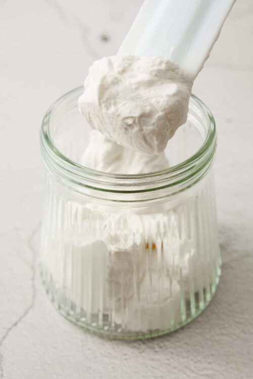 Fluffy homemade whipped cream in a glass jar, perfect for desserts and hot cocoa.