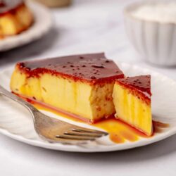 Creamy caramel flan dessert with a shiny caramel glaze on a white plate.