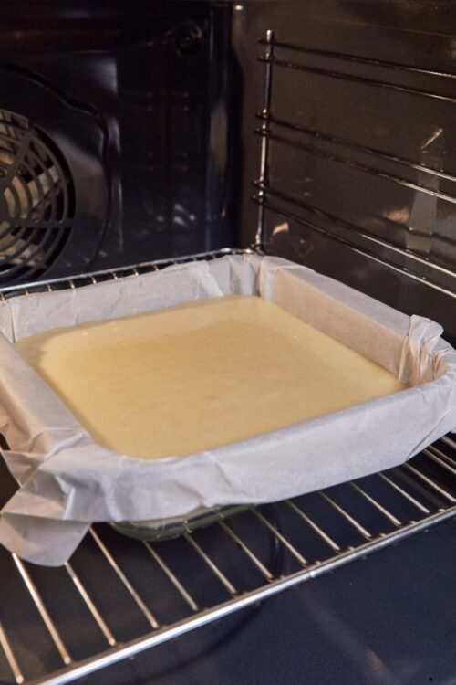 Creamy cake batter in a parchment-lined baking pan in the oven.