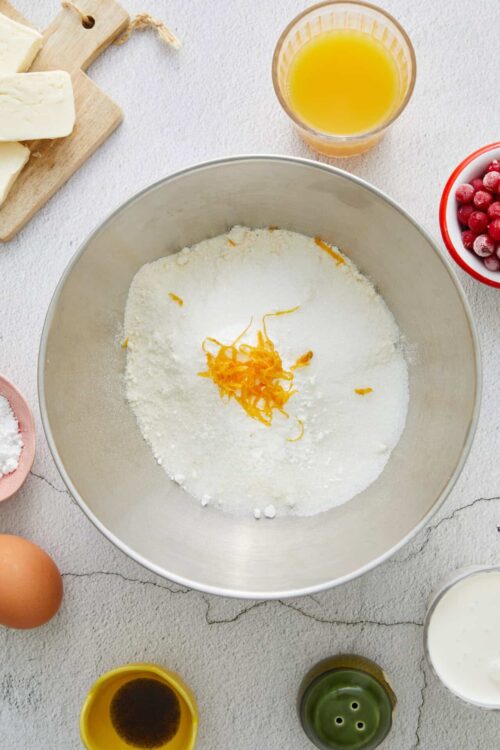Flour mixture with lemon zest for baking recipe, surrounded by baking ingredients on countertop.