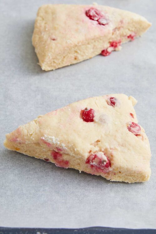 Frozen cherry scones on parchment paper, ready to bake.