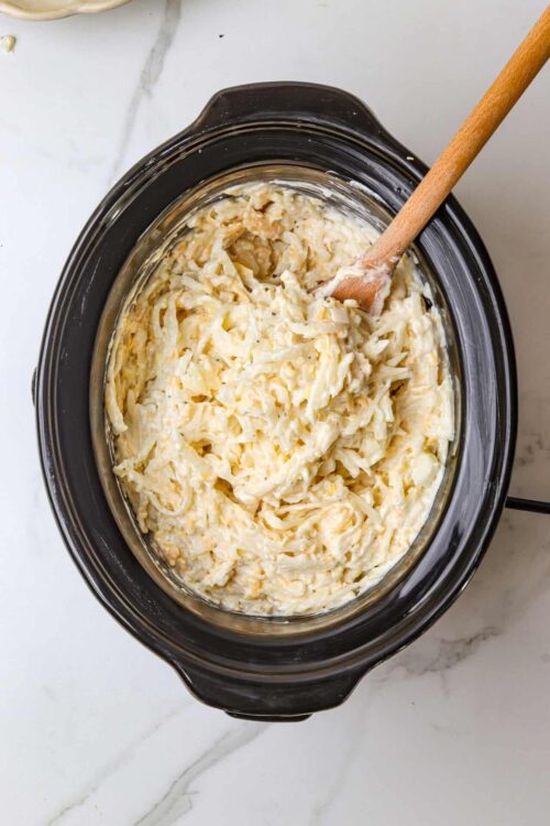 Creamy shredded cheese mixture in a slow cooker, ready for baking or serving.