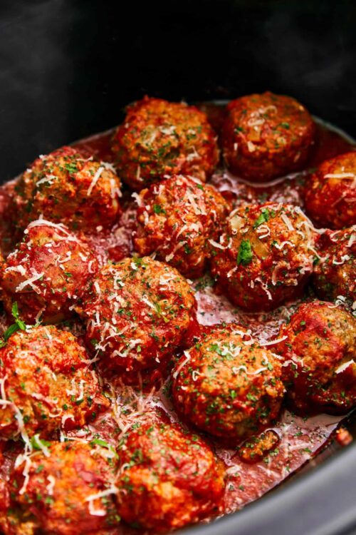 Savory homemade meatballs in tomato sauce garnished with herbs and cheese.