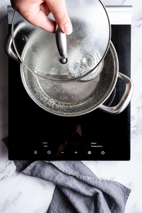 Steaming vegetables in a glass pot on an induction cooktop.