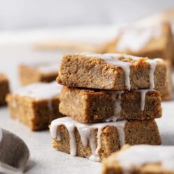 Fudgy pumpkin blondie bars with icing drizzle, gluten-free pumpkin spice dessert.