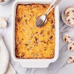 Cheesy baked casserole with ground beef and onions in a white baking dish.