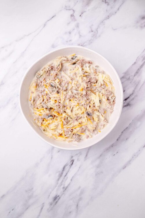 Creamy chicken and mushroom casserole in a white bowl on marble surface.