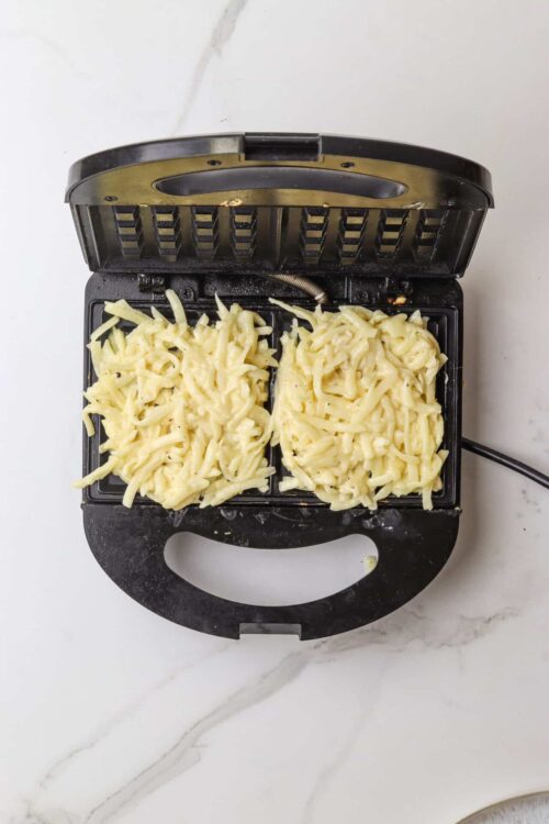 Cheese shredded on a mini waffle maker for a quick cheesy snack or recipe.