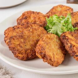 Crispy fried chicken thighs with fresh greens on white plate.