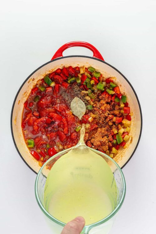 Sautéed vegetable mixture with tomato sauce and spices in a red cast iron skillet.