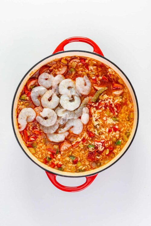 Juicy shrimp in spicy shrimp and rice soup in a red cast-iron skillet.