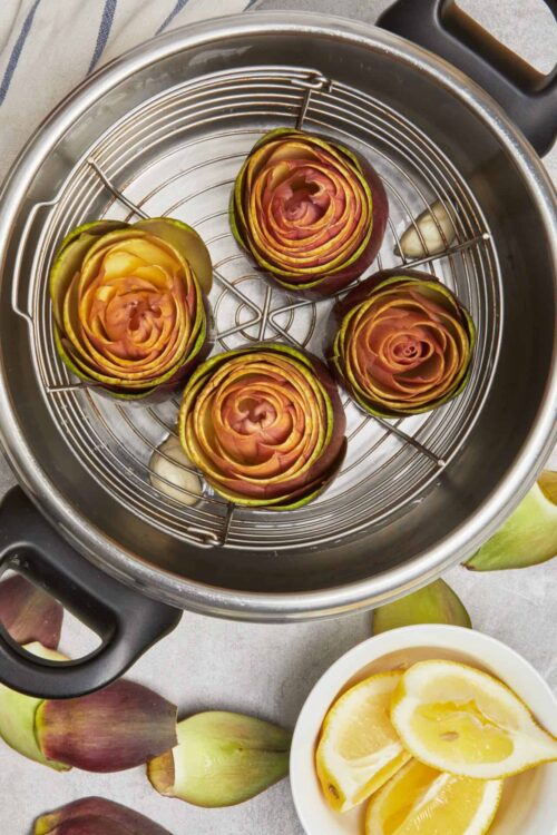 Roasted apple roses in a steamer with lemon slices for a beautiful dessert presentation.