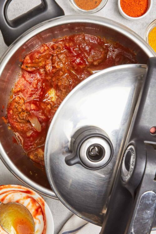 Slow cooker chicken in tomato sauce with spices, ready for shredding.