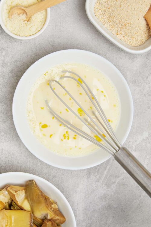 Sweetened condensed milk in a white bowl with a whisk for baking and dessert recipes.