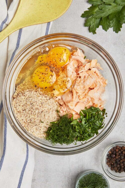 Creamy salmon mixture with eggs, herbs, and bread crumbs in a glass bowl for baking.