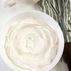 Fluffy whipped cream in a white mixing bowl, ready for baking or dessert topping.