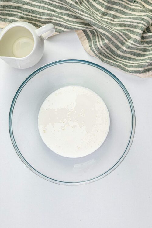Pouring fresh cream into a glass bowl for baking recipes.