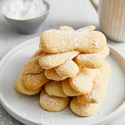 Fluffy homemade sugar cookies with powdered sugar on a white plate.