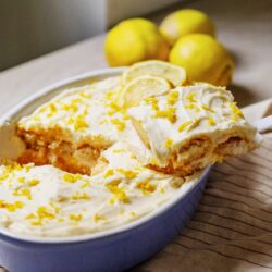 Lemon dessert with lemon zest and whipped cream in a casserole dish.