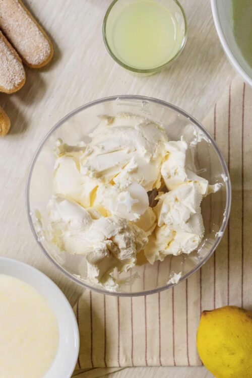 Cream cheese in a clear mixing bowl for cheesecake recipe.