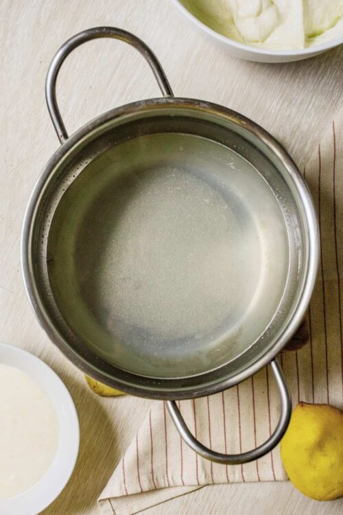 Boiling sugar water mixture in a stainless steel pot for baking recipes.