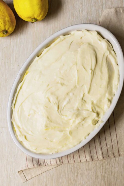 Fluffy homemade mashed potatoes in a white dish with lemons in the background.