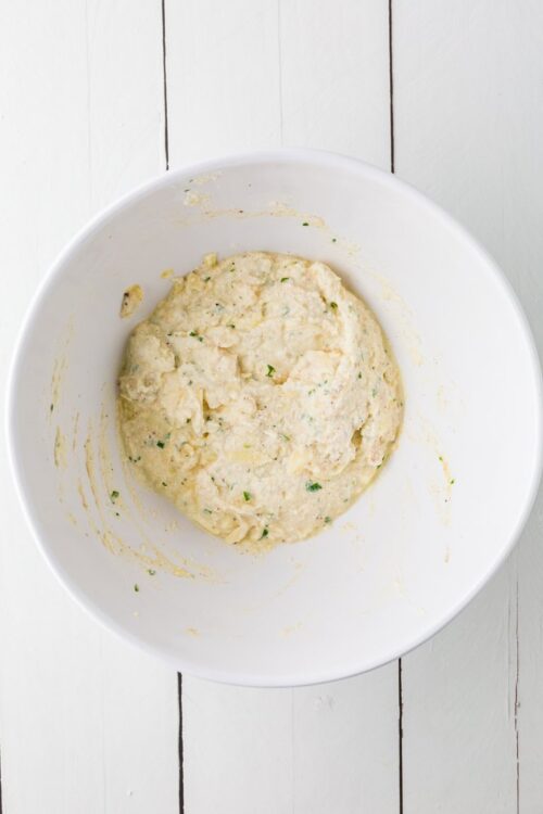 Creamy homemade potato and chive dough mixture in a white bowl for baking or cooking.