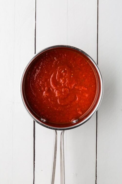 Rich homemade tomato sauce in a stainless steel saucepan.
