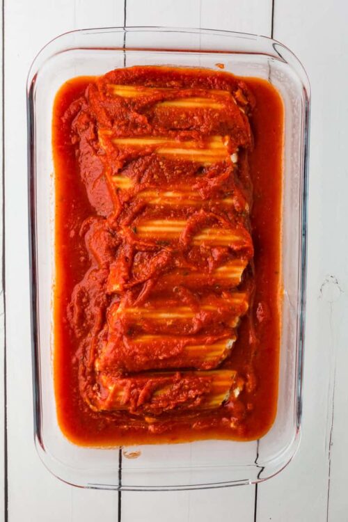 Marinated stuffed cabbage rolls in tomato sauce in glass baking dish.