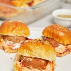Golden baked chicken and cheese sliders on a white plate, soft and savory, perfect for easy family dinners or parties.