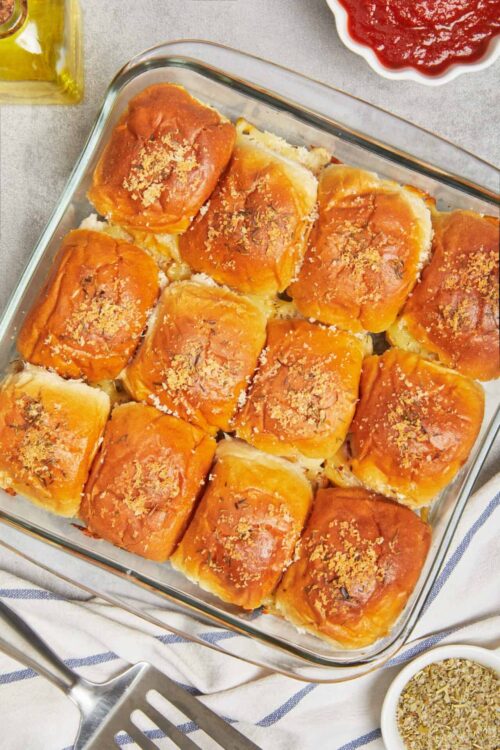 Golden baked chicken breast in a glass dish with herbs and seasoning.