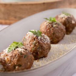 Home-style meatballs served on a white platter with fresh parsley garnish.