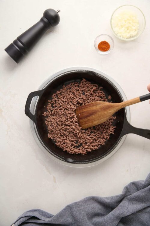 Cooked ground beef in a skillet ready for recipe use, with added spices and ingredients.