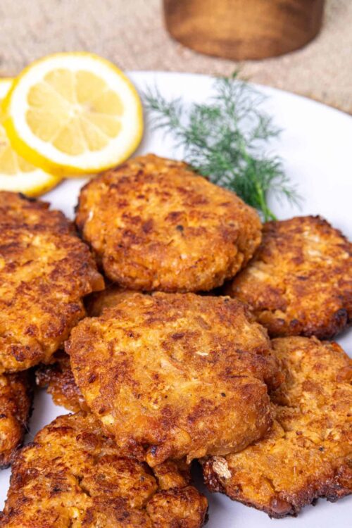 Crispy baked chicken thighs served with lemon slices and fresh herbs.