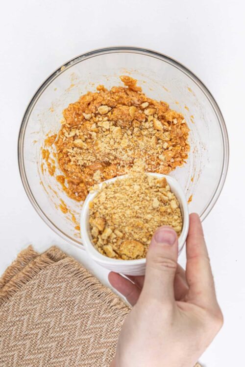 Crushed graham crackers being added to pumpkin pie filling.