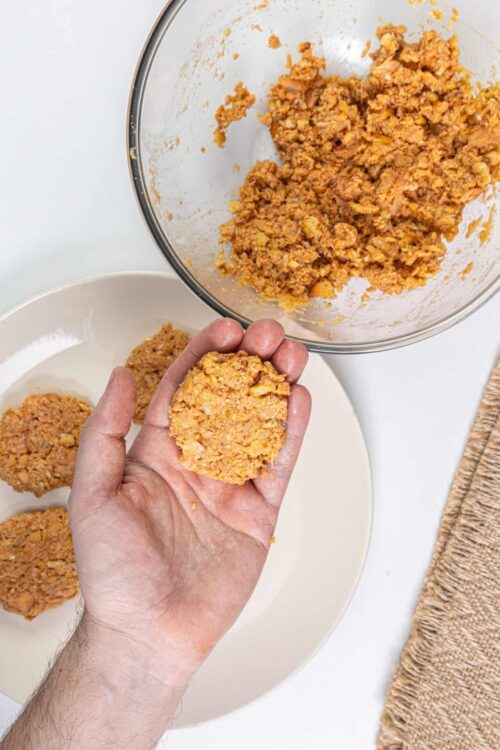 Golden breadcrumb chicken patty being prepared for baking.