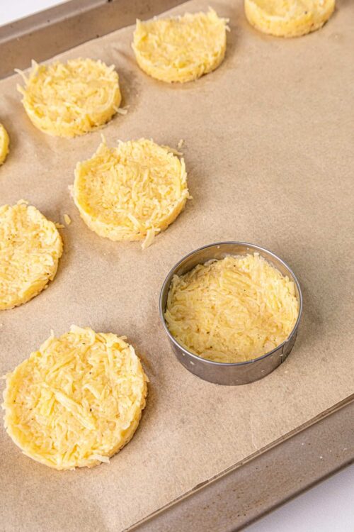 Shredded cheese cupcakes in baking molds on parchment paper, cheese cross-section in background.