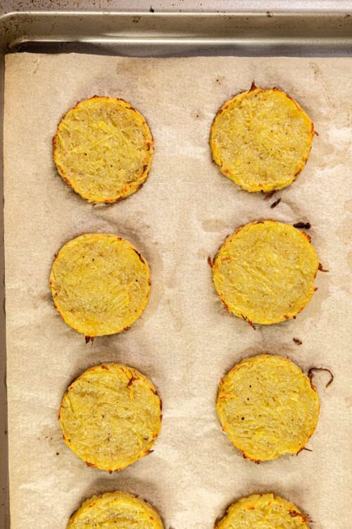 Golden baked potato rounds on a baking sheet with parchment paper.