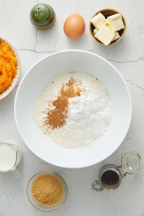 Flour, spices, and baking ingredients in a white bowl for pumpkin baking recipe.