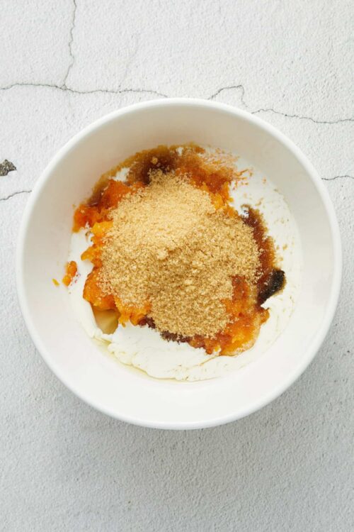 Golden brown sugar and fruit filling layered over creamy whipped cream in a white bowl.