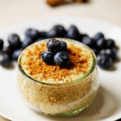 Creamy lemon blueberry dessert in a glass jar with fresh blueberries on top.