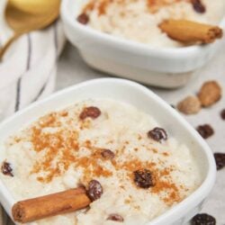 Rich creamy rice pudding with raisins, cinnamon, and a cinnamon stick garnishing a comforting dessert.