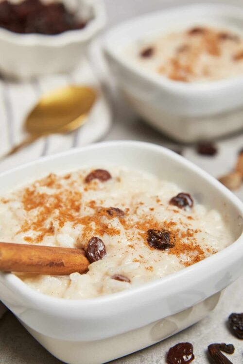 Creamy rice pudding with raisins and cinnamon in a white ceramic dish, served as a delicious dessert.