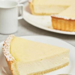 Creamy lemon cheesecake with a graham cracker crust on a white plate.